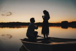 Man proposes to woman on boat at sunset.